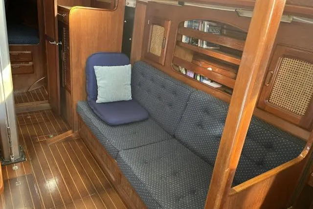 Slide: The Image of Interior of 1985 Islander Peterson 40 sailboat with wooden finish and blue cushioned seating. - 4
