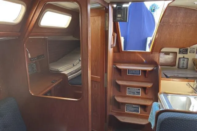 Slide: The Image of Interior of 1985 Islander Peterson 40 sailboat, featuring wooden cabinetry and cozy sleeping quarters. - 7