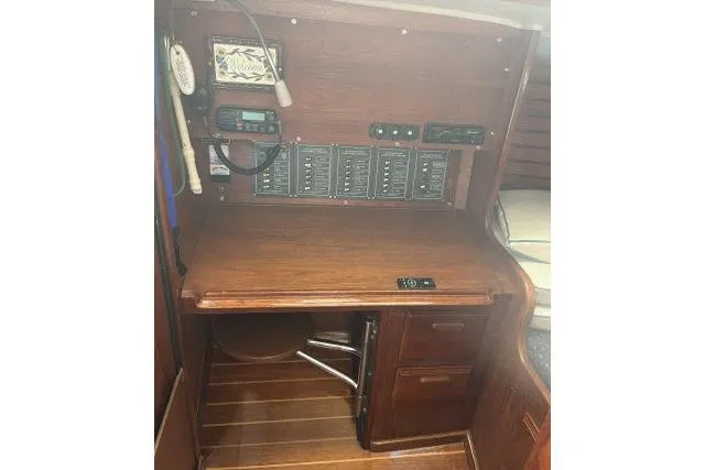Slide: The Image of 1985 Islander Peterson 40 yacht navigation station with control panels and wooden desk. - 8