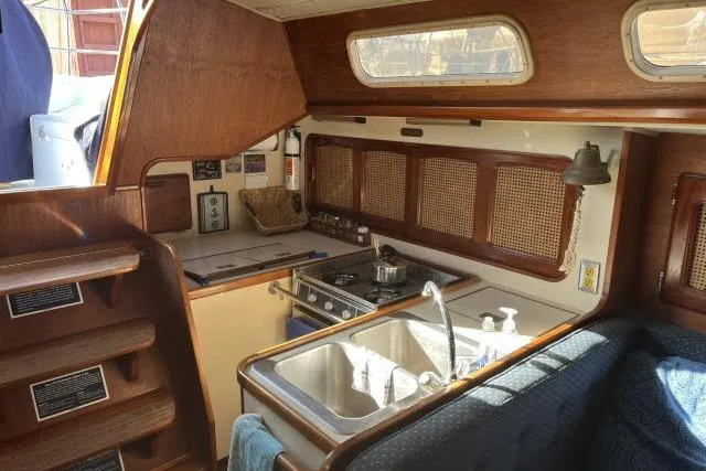 Slide: The Image of Interior of 1985 Islander Peterson 40 sailboat, featuring a compact kitchen with stove and sink. - 9