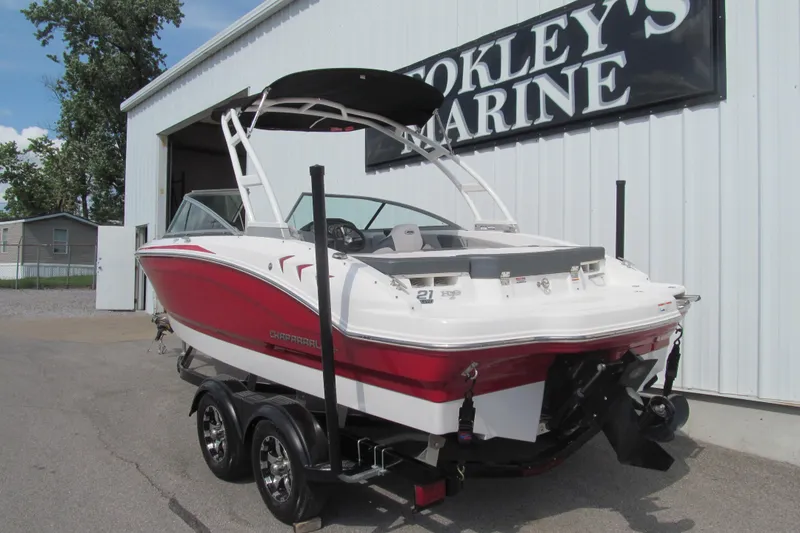 Slide: The Image of 2019 Chaparral 21 H2O Sport boat in red and white, parked outside a marine shop. - 3