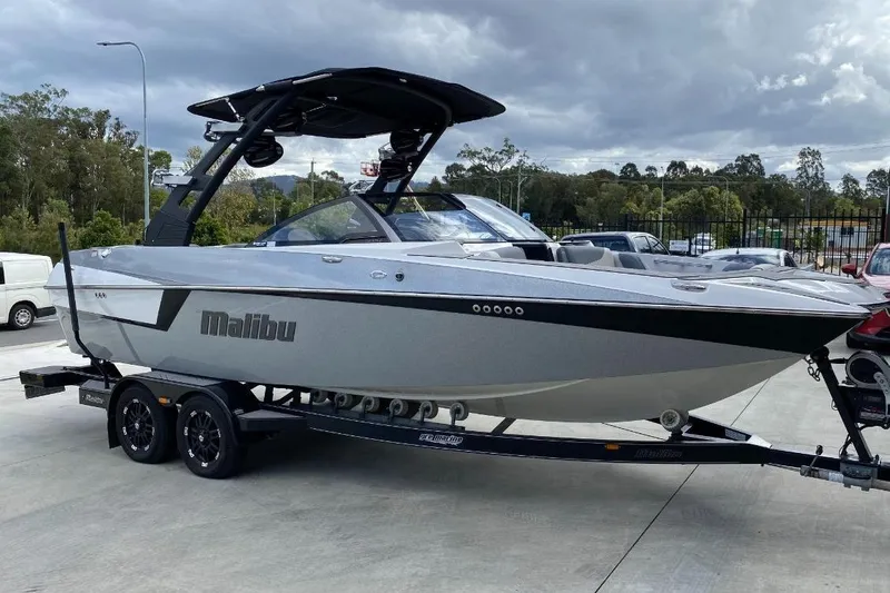 The Image of 2018 Malibu Wakesetter 22 MXZ boat on trailer, parked outdoors under cloudy sky. - 0