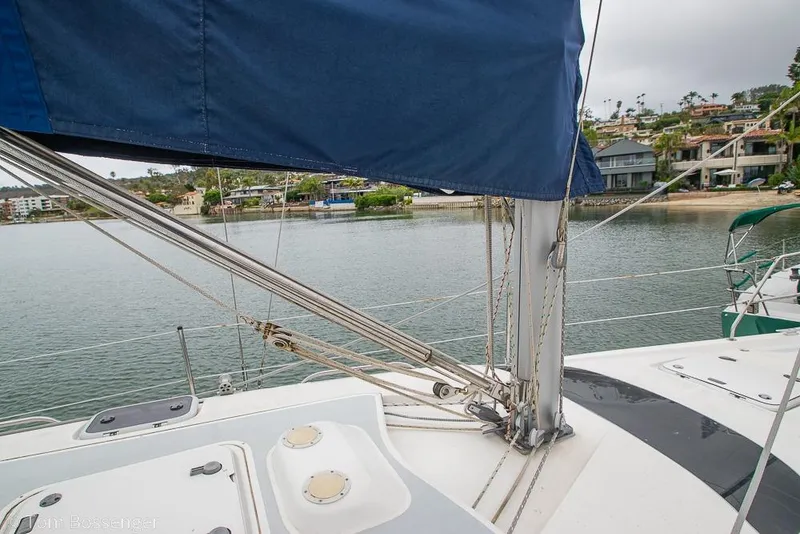 Slide: The Image of Sailboat deck view of 1995 Hunter 336 with blue sail, docked near waterfront homes. - 28