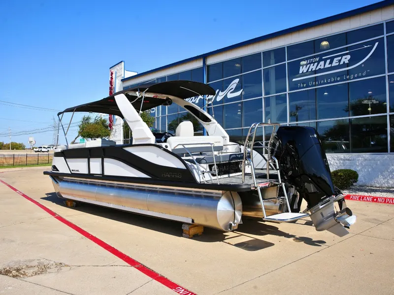 Slide: The Image of A 2027 Harris Grand Mariner 250 pontoon boat is parked on a lot in front of a building. - 2