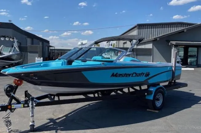 The Image of 2018 MasterCraft ProStar boat on trailer, parked outdoors under a clear blue sky. - 0