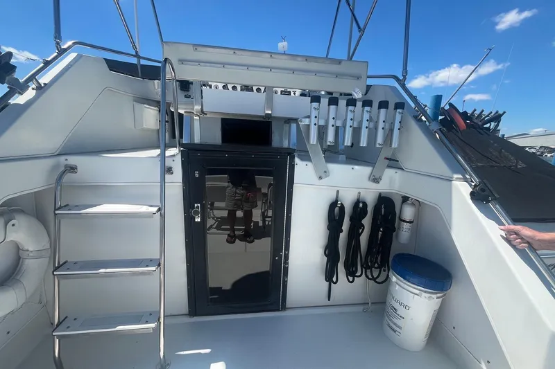 Slide: The Image of 1988 Seafox 29 Flybridge boat deck with storage, ladder, and equipment under a clear blue sky. - 13