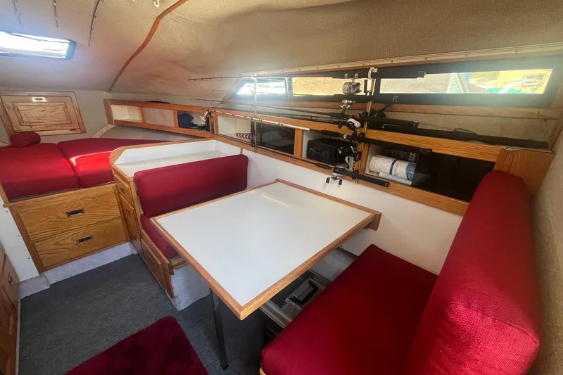Slide: The Image of Interior of 1988 Seafox 29 Flybridge with red seating, dining table, and fishing rod storage. - 15