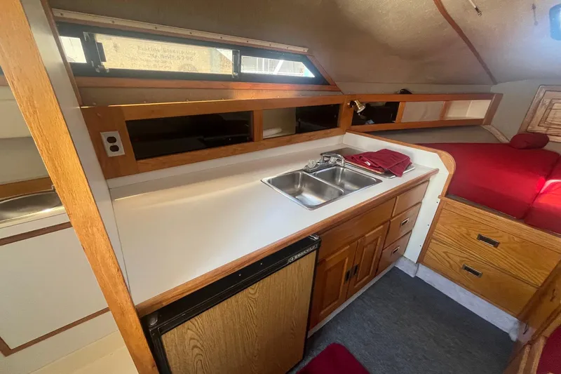 Slide: The Image of 1988 Seafox 29 Flybridge interior with kitchenette, sink, and cozy sleeping area. - 16