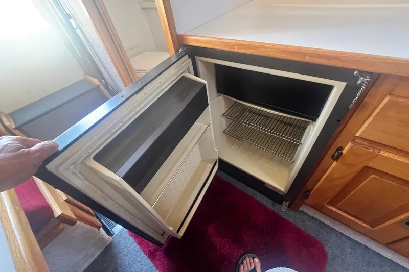 Slide: The Image of Open refrigerator inside 1988 Seafox 29 Flybridge boat, showing interior shelves. - 19