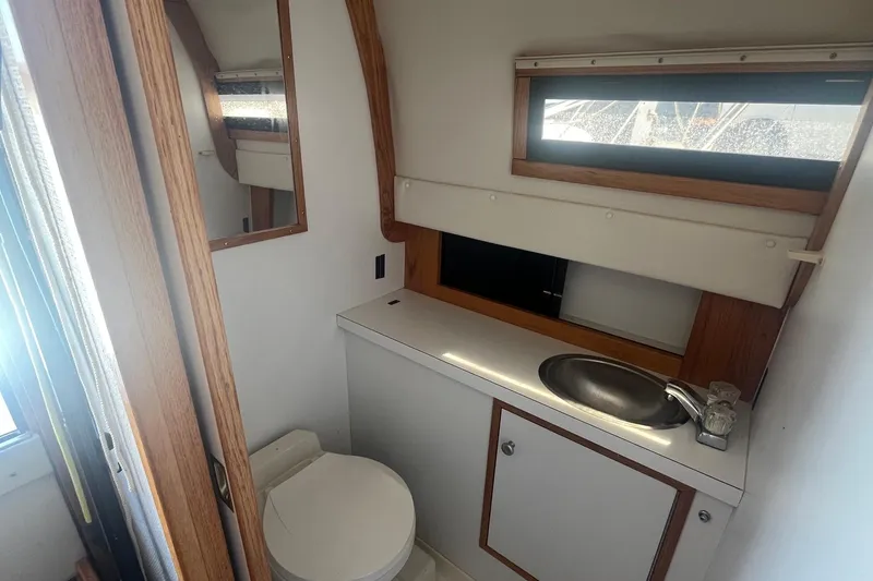Slide: The Image of 1988 Seafox 29 Flybridge boat bathroom with sink, toilet, and window. - 21
