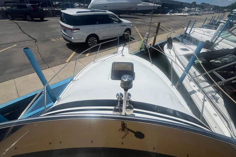 Slide: The Image of 1988 Seafox 29 Flybridge boat docked, viewed from the bow, with nearby parked vehicles. - 5