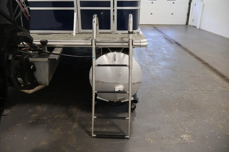 Slide: The Image of 2022 Sylvan 8520 Mirage pontoon boat with ladder and motor in a garage setting. - 33