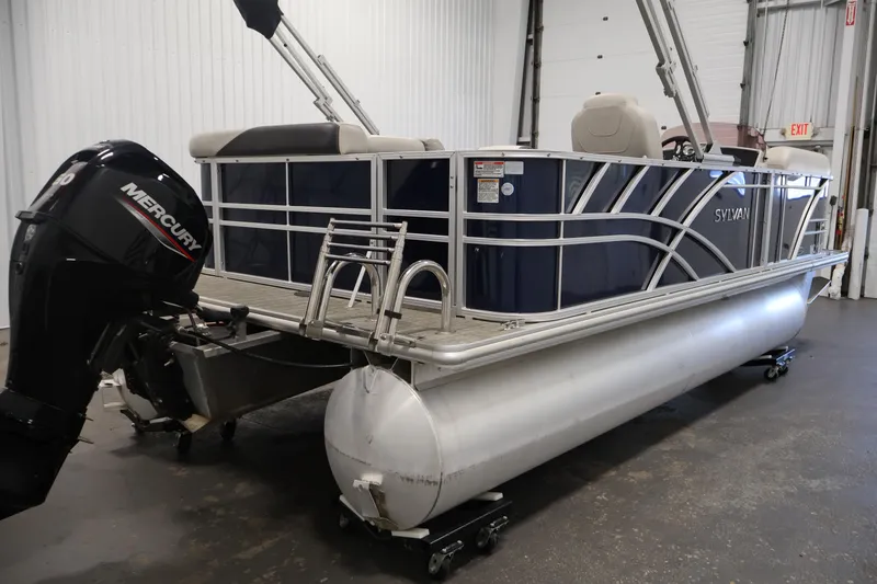 Slide: The Image of 2022 Sylvan 8520 Mirage pontoon boat with Mercury outboard motor in a garage setting. - 5