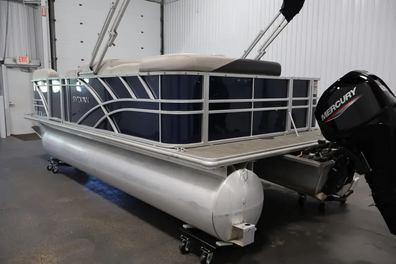 Slide: The Image of 2022 Sylvan 8520 Mirage pontoon boat with Mercury outboard motor in a garage setting. - 7