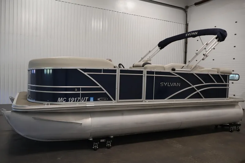 Slide: The Image of 2022 Sylvan 8520 Mirage pontoon boat in a showroom, featuring sleek design and blue accents. - 8