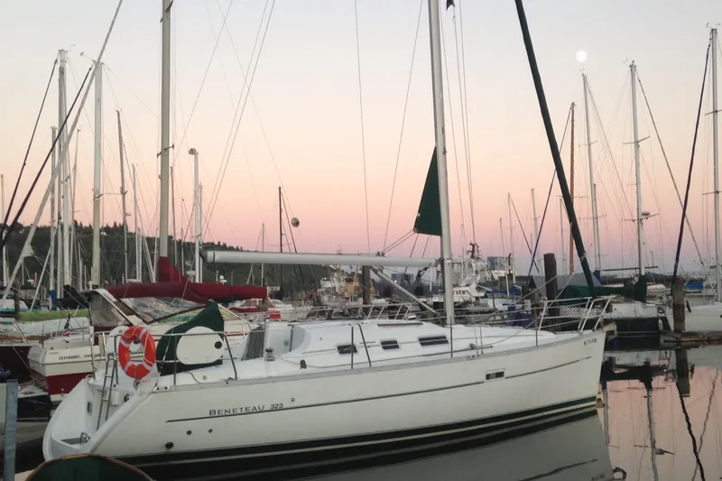 The Image of 2006 Beneteau 323 sailboat docked at sunset with masts in the background. - 0