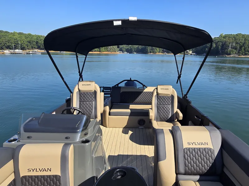 Slide: The Image of The image shows a 2027 Sylvan MIRAGE X3 ULZ pontoon boat on a calm lake. - 21