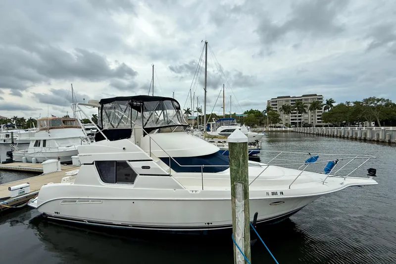 The Image of 2000 Silverton 351 Sedan yacht docked at marina under cloudy skies. - 0
