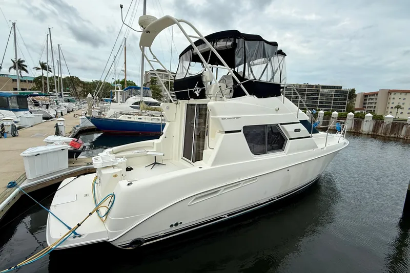 Slide: The Image of 2000 Silverton 351 Sedan yacht docked at marina, featuring sleek design and spacious deck. - 2
