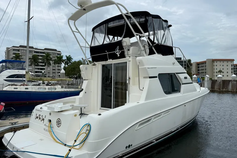 Slide: The Image of 2000 Silverton 351 Sedan yacht docked at marina, featuring sleek design and spacious deck. - 3