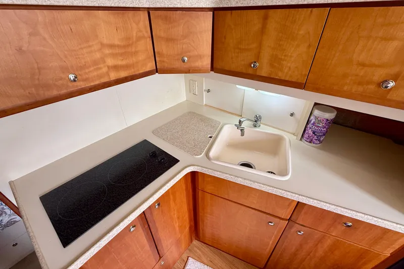 Slide: The Image of 2000 Silverton 351 Sedan kitchen with stove, sink, and wooden cabinets. - 35