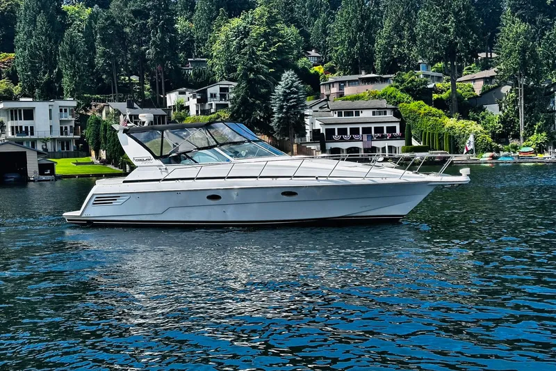 The Image of 2000 Trojan 400 Express yacht cruising on a scenic lake with waterfront homes. - 0
