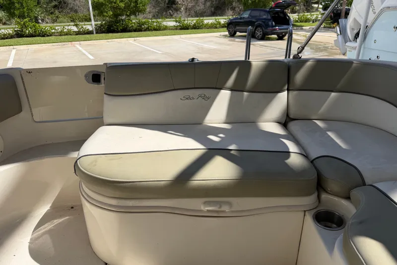 Slide: The Image of 2006 Sea Ray 240 Sundeck boat interior with cushioned seating in a parking lot. - 33