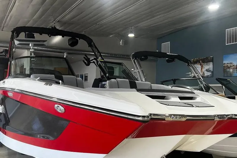 The Image of 2022 MasterCraft X24 boat in showroom, featuring sleek red and white design. - 1