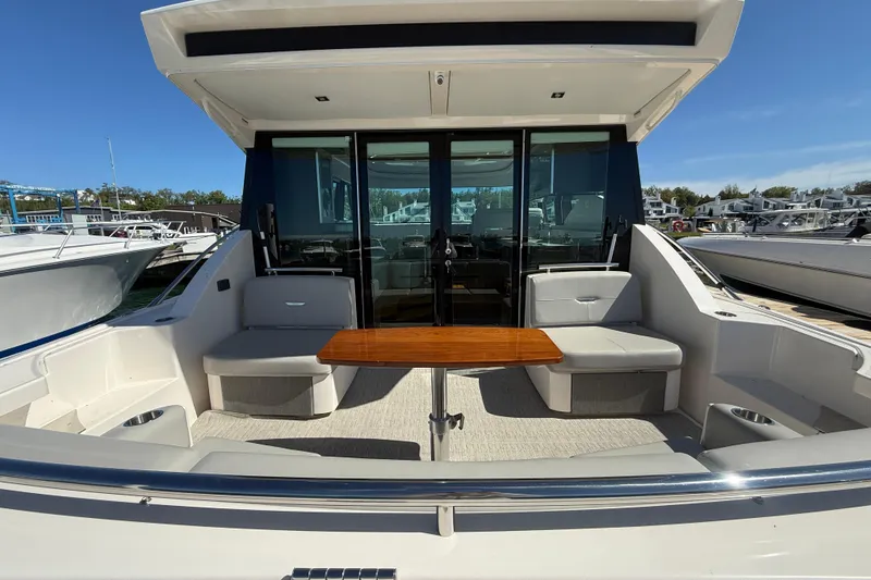Slide: The Image of 2019 Tiara Yachts C44 Coupe with outdoor seating and table, docked at marina. - 11