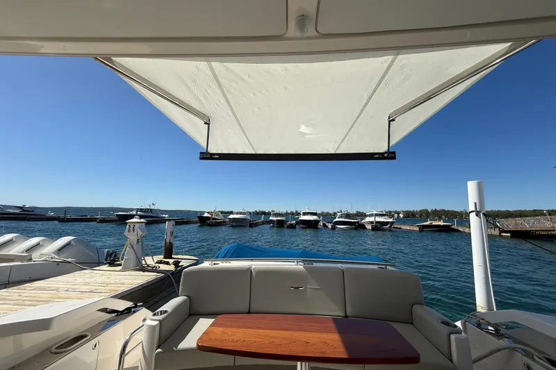 Slide: The Image of 2019 Tiara Yachts C44 Coupe at marina, featuring spacious seating and sunshade. - 13