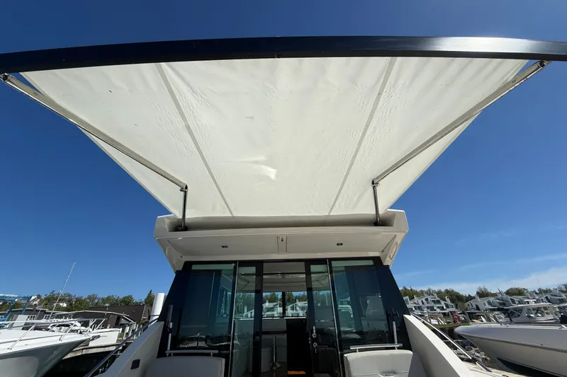 Slide: The Image of 2019 Tiara Yachts C44 Coupe with extended canopy under clear blue sky. - 14