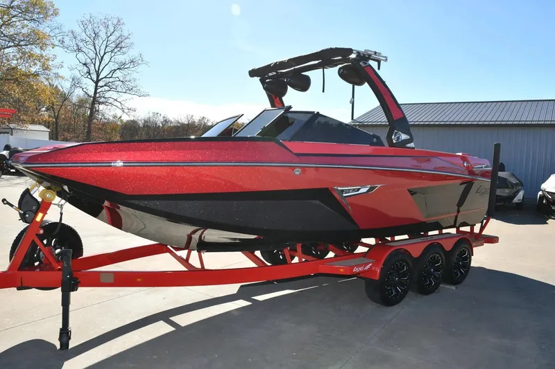 The Image of 2022 Tigé 24RZX boat in vibrant red on a matching trailer, parked outdoors. - 1