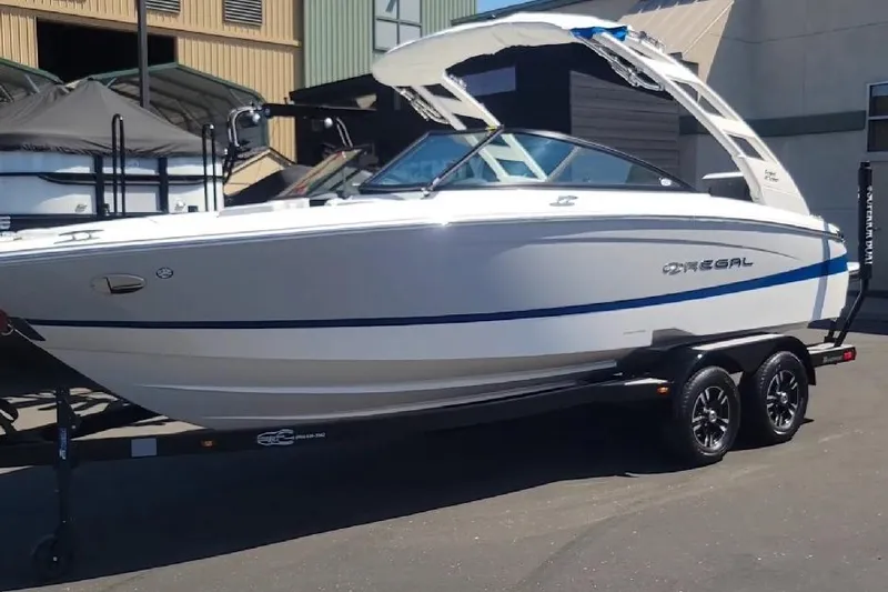 The Image of 2023 Regal LS2 boat on trailer, sleek design, parked outdoors. - 1
