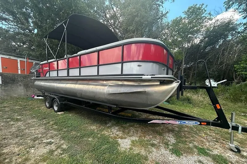 The Image of 2024 Bentley Pontoons 240 Navigator on trailer, featuring red and silver design with canopy. - 1