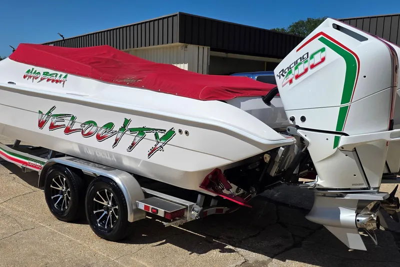 Slide: The Image of 2024 Velocity 290 Sport Cruiser with Racing 400 engine, red cover, on a trailer. - 2