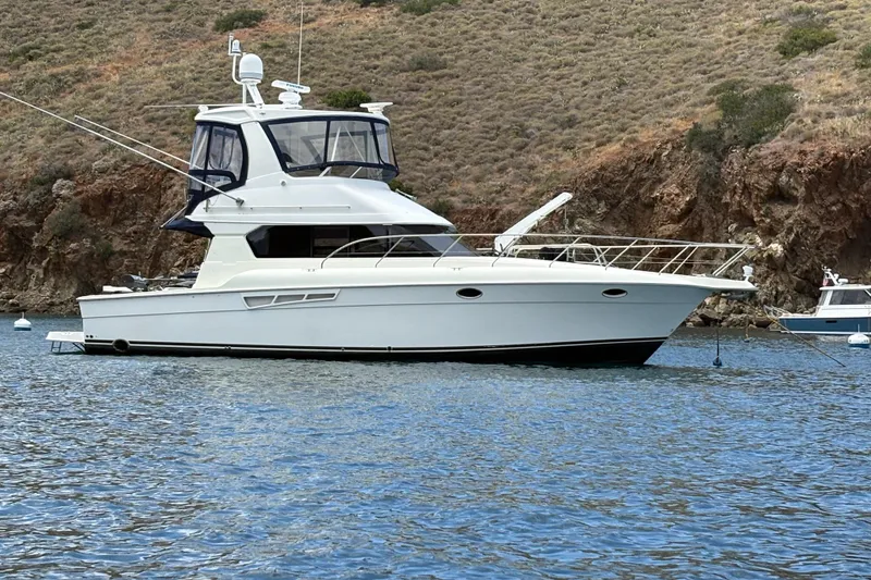 Slide: The Image of 2000 Silverton 42 Convertible yacht anchored in scenic coastal waters. - 1