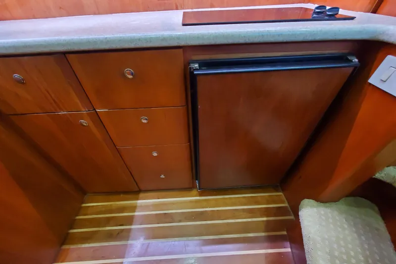 Slide: The Image of Interior of 2000 Silverton 42 Convertible yacht with wooden cabinetry and compact fridge. - 19