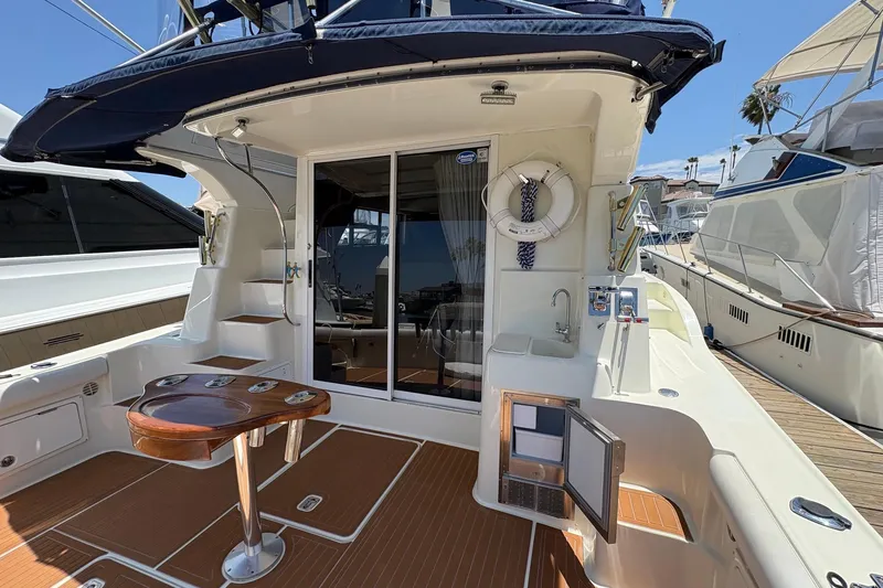 Slide: The Image of 2000 Silverton 42 Convertible yacht deck with seating, table, and sliding glass door. - 3
