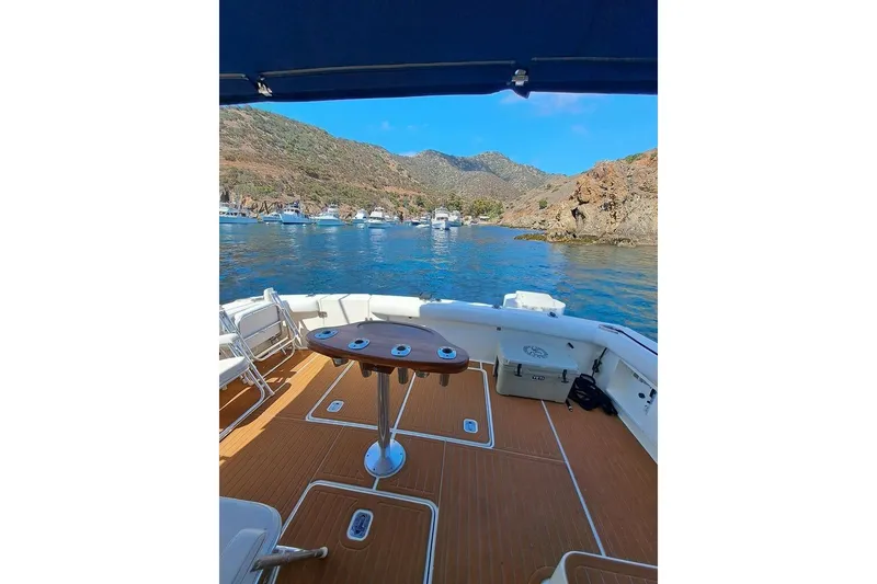 Slide: The Image of 2000 Silverton 42 Convertible yacht with scenic coastal view and clear blue waters. - 50
