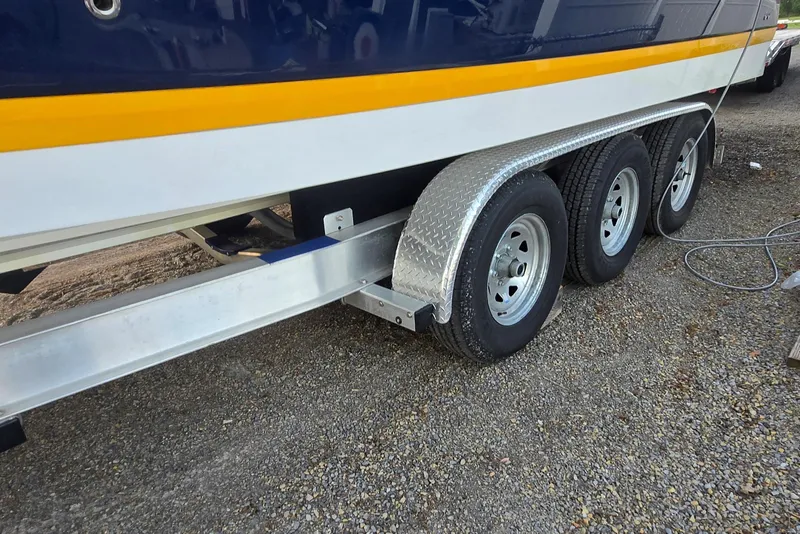 Slide: The Image of Trailer with triple axles for 2013 Cobalt 296 boat on gravel surface. - 10