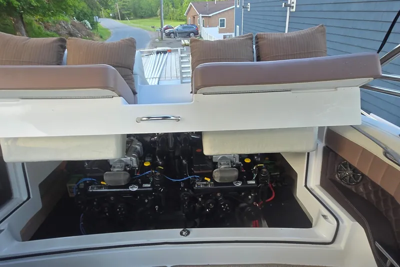 Slide: The Image of 2013 Cobalt 296 boat engine compartment with cushioned seating and visible dual engines. - 12