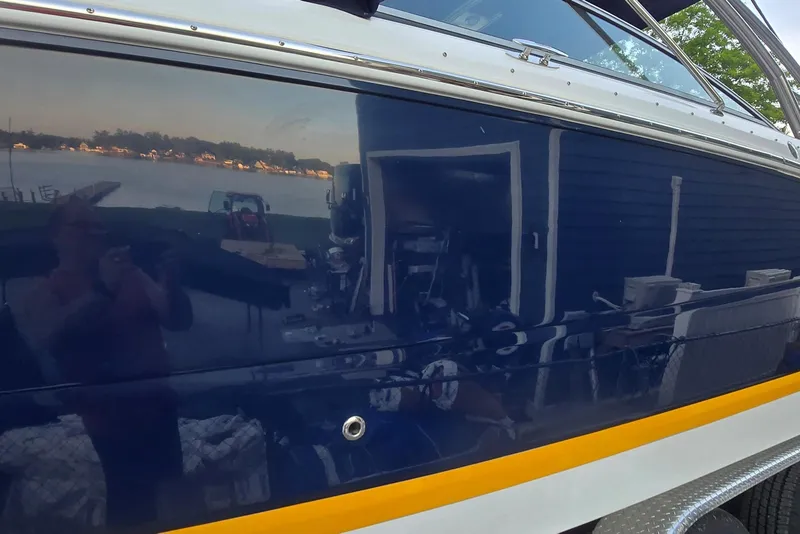 Slide: The Image of 2013 Cobalt 296 boat with reflective blue hull near a lakeside view. - 14