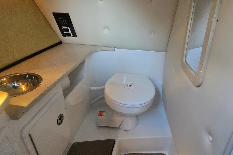 Slide: The Image of Compact bathroom in a 2013 Cobalt 296 boat, featuring a toilet and sink. - 15