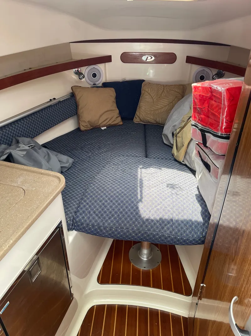 Slide: The Image of The cabin of the 2008 Pursuit OS 285 Offshore features a cozy bed with pillows and storage. - 0