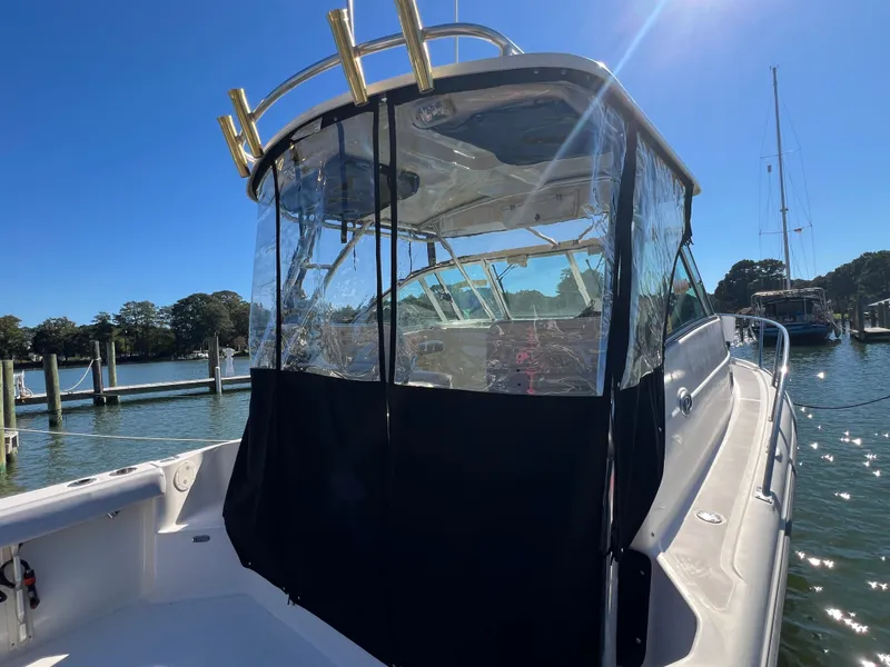 Slide: The Image of A 2008 Pursuit OS 285 Offshore with clear covers in a harbor, surrounded by water and trees. - 37