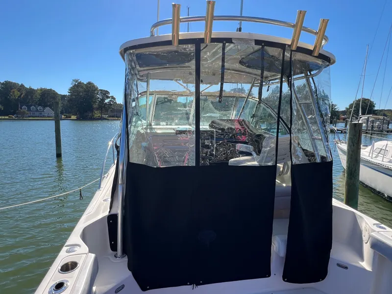 Slide: The Image of The 2008 Pursuit OS 285 Offshore is docked. It features a covered cockpit and clear protective curtains. - 35