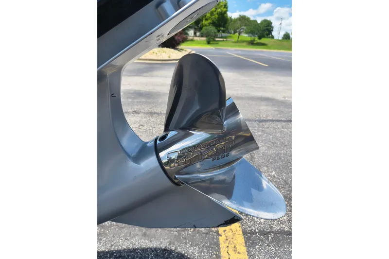 Slide: The Image of 2022 Ranger Z518 boat propeller, shiny metal finish, parked on asphalt with greenery background. - 6