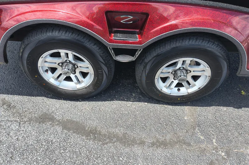 Slide: The Image of 2022 Ranger Z518 trailer wheels on asphalt, featuring shiny silver rims and red fender. - 8