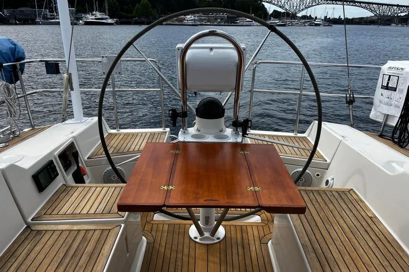 Slide: The Image of Cockpit of 2004 Hanse 411 sailboat with wooden table and steering wheel, docked by the water. - 27