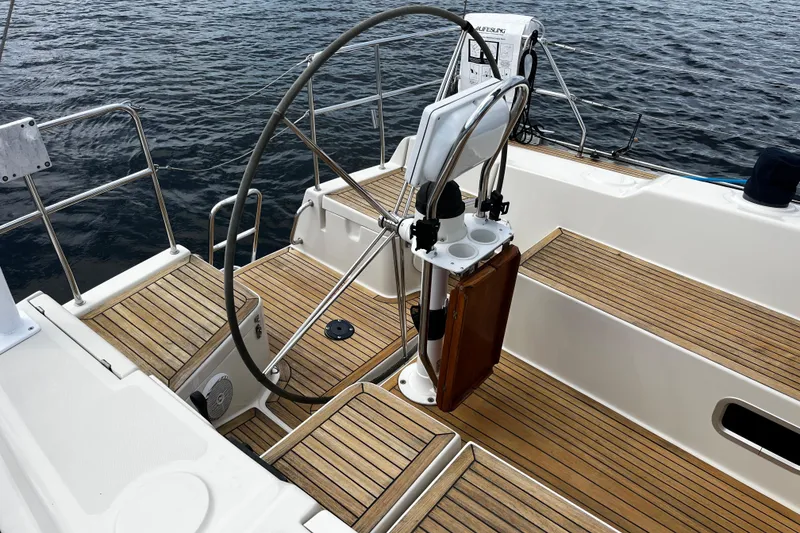 Slide: The Image of 2004 Hanse 411 sailboat cockpit with wooden deck and steering wheel on calm water. - 32